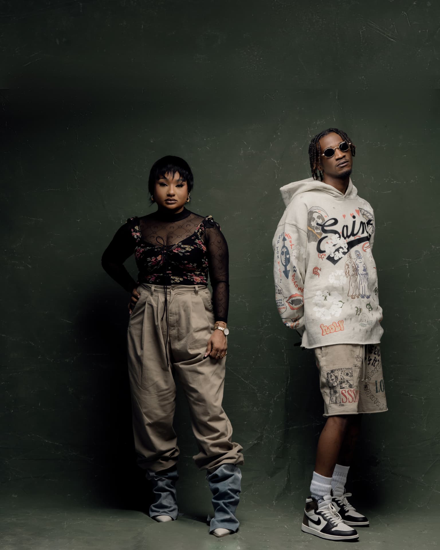 Aika & Nahreel standing against a deep green studio wall