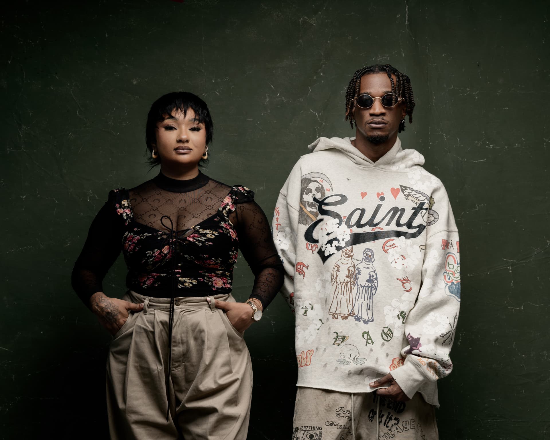 Aika & Nahreel wide studio portrait against a green wall